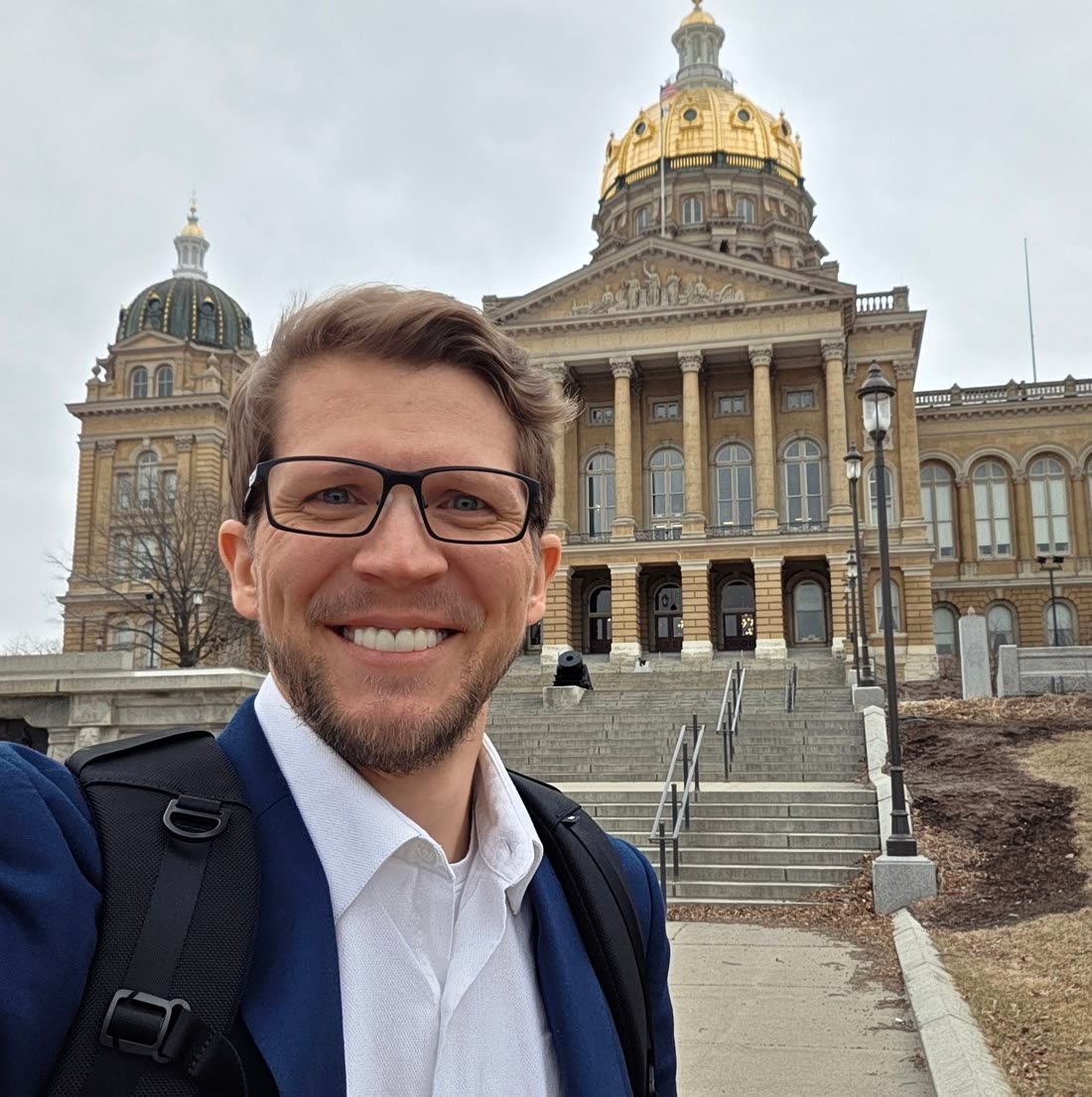 Brett Mohler outside the Iowa State Capitol, backpack over one shoulder